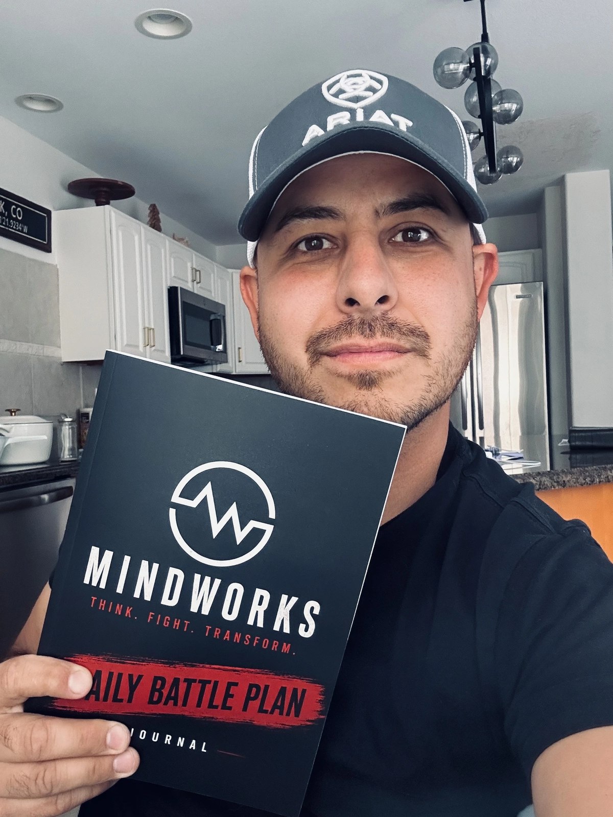 Tim holding the MindWorks Daily Battle Plan Journal in his kitchen